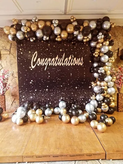 A stunning "Congratulations" backdrop with a starry night theme and a black, gold, and silver balloon frame, perfect for any major achievement.