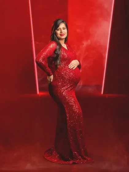 A full-length portrait of a mom-to-be in a stunning red sequin gown, showcasing her pregnancy glow.