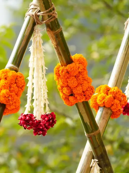 A close-up of the floral tassels, made with marigolds, tuberoses, and red flowers, hanging from the bamboo backdrop.