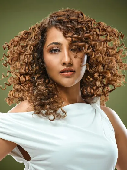 This full-volume curly style shows how brunette color can make curls pop. The highlights are carefully placed to catch the light and define each curl.