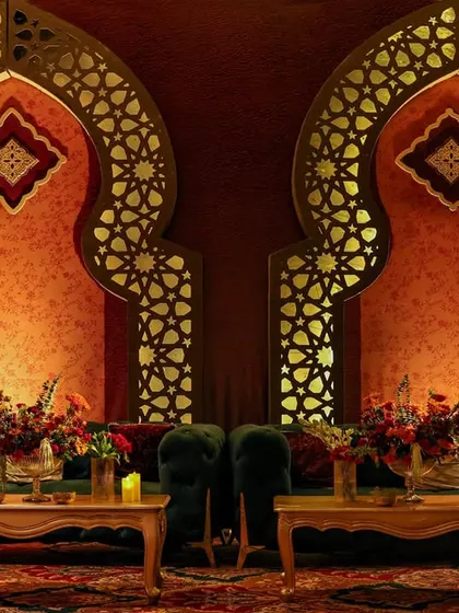 A lounge setting framed by two grand, backlit arches with intricate geometric patterns. This architectural element is key to the Indo-Islamic aesthetic, creating both beauty and structure.