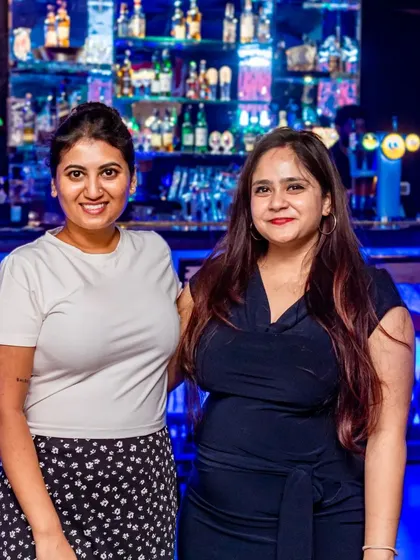Two friends posing in front of my fully stocked, beautifully lit bar. It's a centerpiece of the pub for a reason.