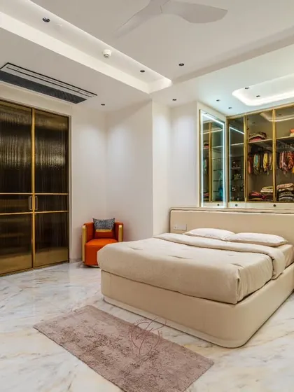 This angle shows the full scale of the room, with the plush bed, the elegant chandelier over the closet, and the beautiful veined marble flooring that adds a layer of opulence.