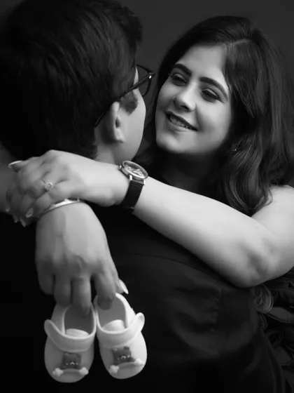 A close-up on the details that matter most. The tiny baby shoes held by the loving couple create a sentimental and timeless black and white portrait.