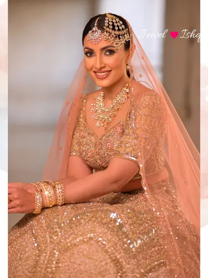 A graceful portrait of the bride seated, her pastel lehenga spread around her. The polki jewellery adds a touch of grandeur to the soft, romantic look.