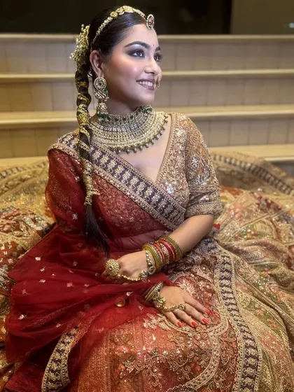 A beautiful portrait showcasing the bride's braided hairstyle and the intricate details of her lehenga. The makeup is kept soft and glowing to match the overall aesthetic.
