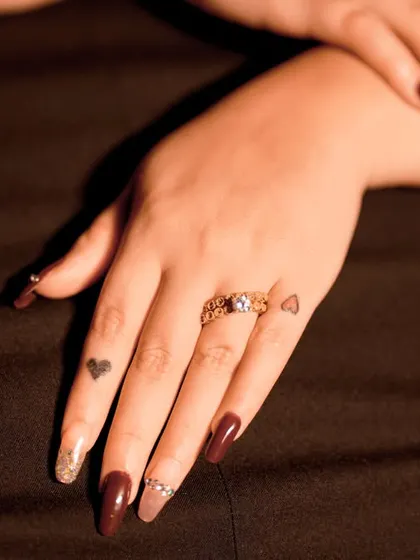 A detailed shot of the engagement ring on her hand, complete with cute finger tattoos.