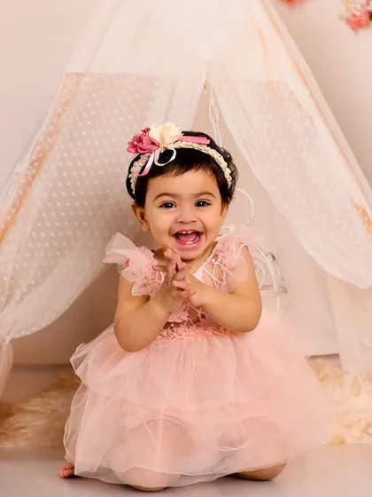 This portrait captures a huge, joyful laugh. The soft, romantic lighting and tent prop create a dreamy and whimsical feel.