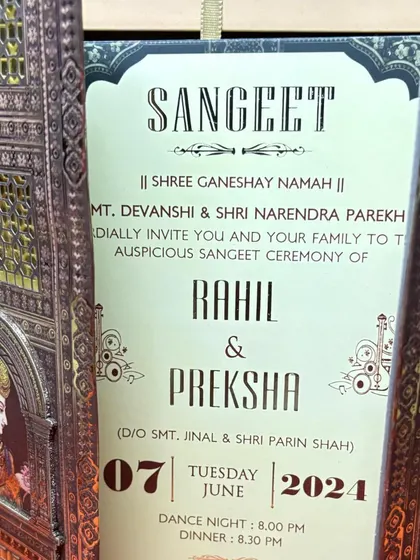 A Sangeet invitation is revealed as the intricate, laser-cut doors of the card are opened, creating a moment of anticipation and delight.