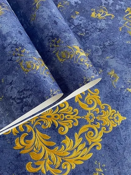 A close-up of a royal blue wallpaper with a textured finish and an ornate gold damask design.