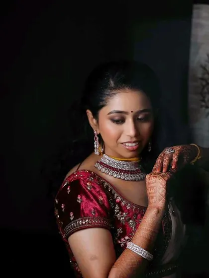 A more artistic portrait from the reception. The soft lighting highlights the flawless finish of her makeup and the richness of her velvet blouse.