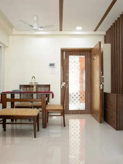 A traditional dining setup with a dark wood table and chairs, complemented by a matching crockery unit and a decorative door.