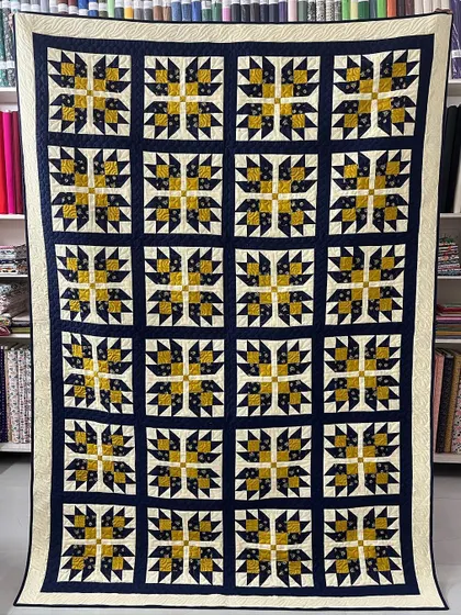 A "Bear Paw" quilt in classic navy and gold. This traditional pattern is a favorite among quilters, and this piece was made by a participant in one of our workshops.