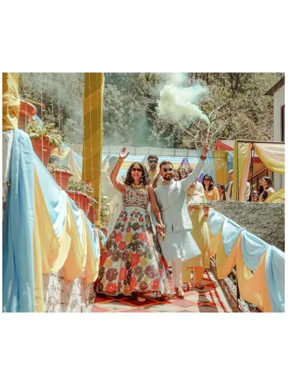 A joyful shot of the couple's grand entrance at their Haldi ceremony, complete with colored smoke. It's a moment that's both fun and cinematic.