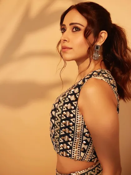 A close-up of Nushrratt Bharuccha in a custom outfit for her movie promotions. The geometric-patterned crop top and vest are so unique.
