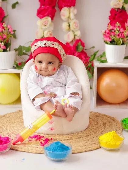 A wide shot of the Holi mini-session setup, showing the colorful powders, balloons, and a happy baby ready to celebrate.