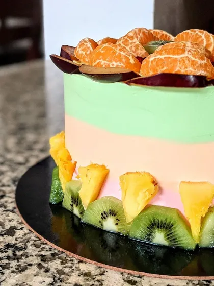Another angle of the tri-color fresh fruit cake, highlighting the texture and vibrant colors of the fruit and frosting.