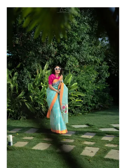 A vertical composition from the same series, this shot provides a clear, full-length view of the saree. The framing through the leaves adds depth and a sense of being in a private garden.