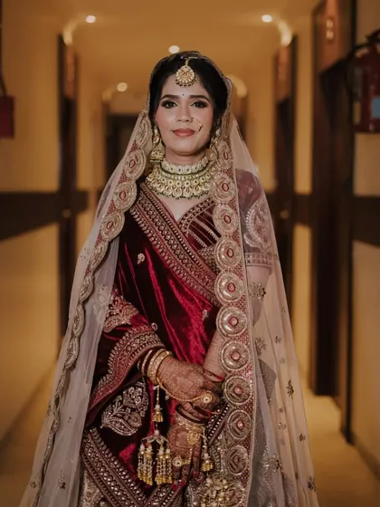 A full-length portrait in a hallway, showcasing the grandeur of her bridal lehenga and the elegance of her posture.