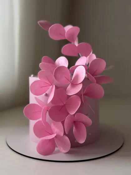 A modern pink cake with a cascade of stylized, handcrafted wafer paper flowers. This technique is perfect for creating contemporary and artistic designs.