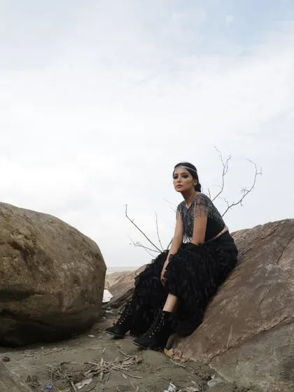 Part of a conceptual outdoor shoot, this look features a black ruffled skirt and embellished top set against a rocky, natural landscape. The styling was intended to create a dramatic, almost elemental fashion story.