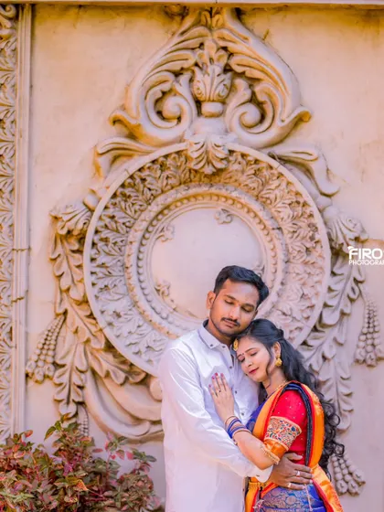 A quiet, intimate moment of a couple in traditional attire. The intricate wall carving provides a beautiful and detailed backdrop.