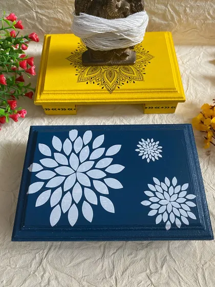 The yellow chowki with a Ganesha idol, and a blue chowki with a white floral stencil. These make great return gifts for festive occasions.