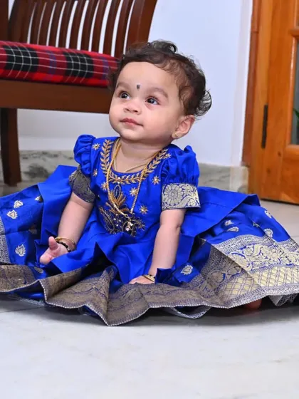 A sweet moment captured in a custom traditional dress. The rich color and classic design of this Pattu Pavadai make it a timeless piece, perfect for passing down as a family heirloom.