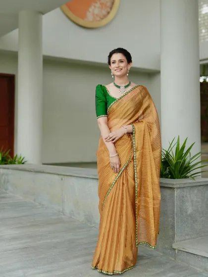 A full-length shot of the golden tissue silk saree, showcasing its lightweight and elegant drape.