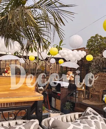 An overview of an outdoor baby shower venue I decorated. I used hanging paper lanterns and balloon clouds to decorate the space, creating a festive and cohesive look throughout the area.