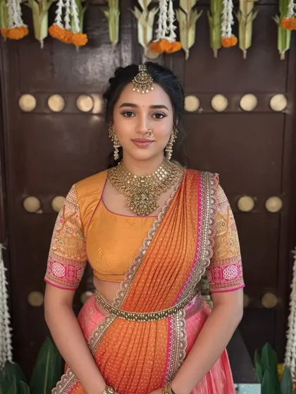 A beautiful portrait showcasing the traditional half-saree and the simple, elegant makeup that enhances the bride's youthful charm.