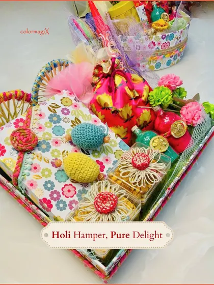 This unique heart-shaped tray is a creative way to present a Holi gift. It's filled with a notebook, crochet items, and jars of treats, offering a mix of utility and indulgence.