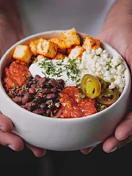 Here's my signature Mexican Burrito Bowl, held with care. It's a vibrant mix of seasoned rice, beans, paneer, and fresh salsa, all in one satisfying meal.