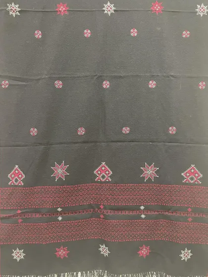 This black woollen shawl features a striking red border and motifs from Kasuti and Negi embroidery traditions. It's a bold and beautiful piece to keep you warm.