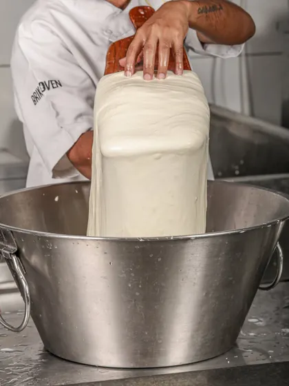 Using a wooden paddle, our cheesemaker continues to stretch and fold the mozzarella. This technique, honed over years, ensures a consistent, smooth, and supple texture in every ball of cheese.