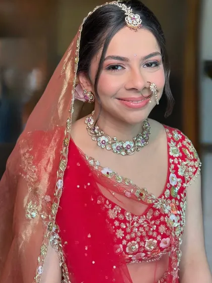 The complete look with the dupatta and nath set. The subtle makeup ensures that the focus remains on the bride's natural beauty and her stunning red outfit.