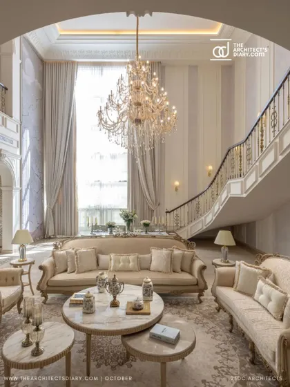 The grand staircase and living area of The Ivory Royale, viewed from an elevated perspective. The sweeping curve of the staircase is a central design feature, creating a sense of drama and opulence.