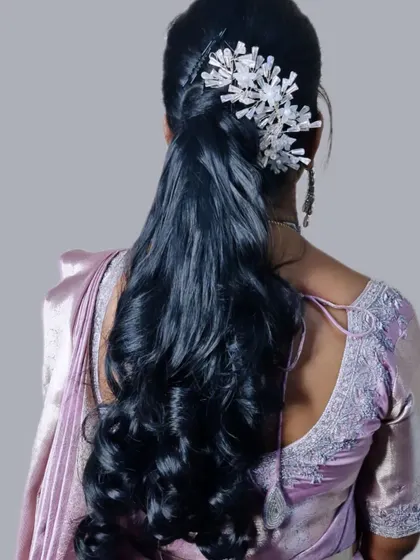 A modern and sleek half-up ponytail with soft waves. The look is elevated with a striking white crystal accessory, making it a great choice for a contemporary party look.