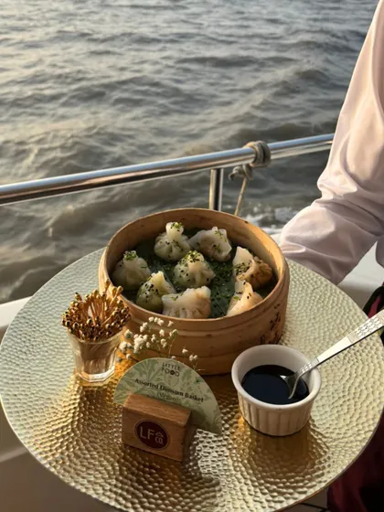 A server presenting a bamboo steamer of assorted dim sum during a yacht party. We ensure that even on a moving boat, the food is fresh, hot, and beautifully presented.