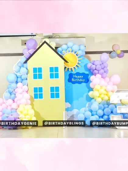 A clean and bright Peppa Pig backdrop, featuring the iconic yellow house, a sunny sky, and a pastel balloon garland.
