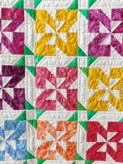 A close-up of a colorful pinwheel quilt, showing the custom quilting in each block.