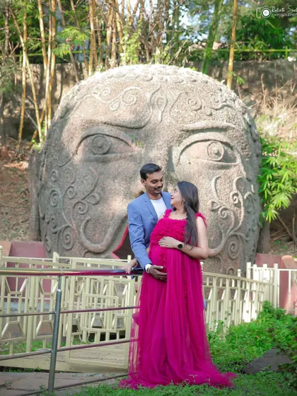 A striking wide shot of the couple posing in front of a large stone sculpture. This shows how we can incorporate unique location features into your photoshoot.