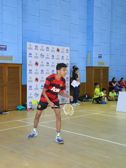A young player in a Manchester United jersey gets into position for a backhand shot during a tournament game.
