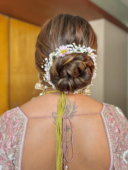 A classic and neat bridal bun adorned with a garland of fresh pink and white flowers.
