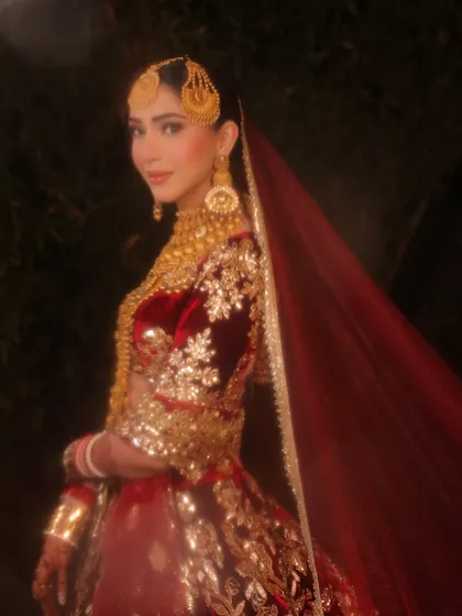 A dreamy, soft-focus shot capturing the richness of the velvet and the glow of the makeup. The side profile highlights the intricate hairpiece and the flawless finish of her reception look.