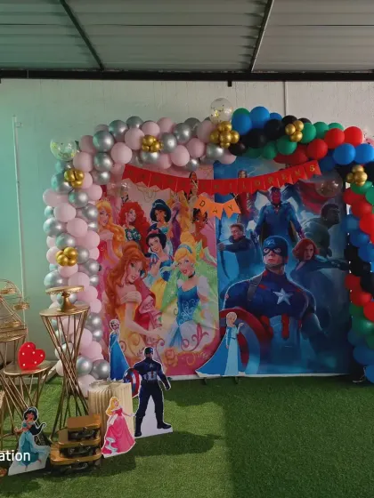 A straight-on view of the dual-theme backdrop, with a pink and silver balloon arch on the princess side and a colorful one on the superhero side.