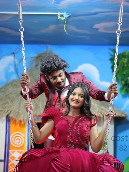 A playful moment on a studio swing set. The couple is dressed in matching red and maroon outfits, showcasing our fun and colorful options for pre-wedding photoshoots.