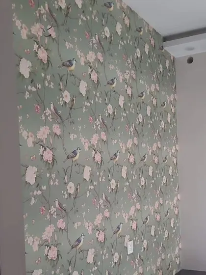 A lovely wallpaper with a pattern of birds and cherry blossoms on a sage green background.