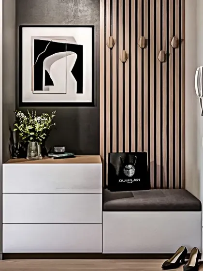 A sleek and modern foyer unit with handleless white drawers and a comfortable seating bench. The vertical wood slats with hooks provide a stylish place to hang coats and bags.