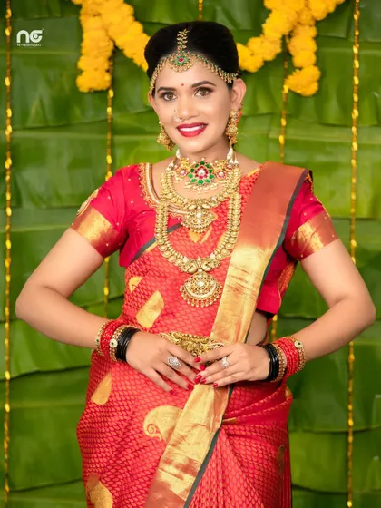 A model styled in a red saree with a grand temple jewellery set, including a statement matha patti.
